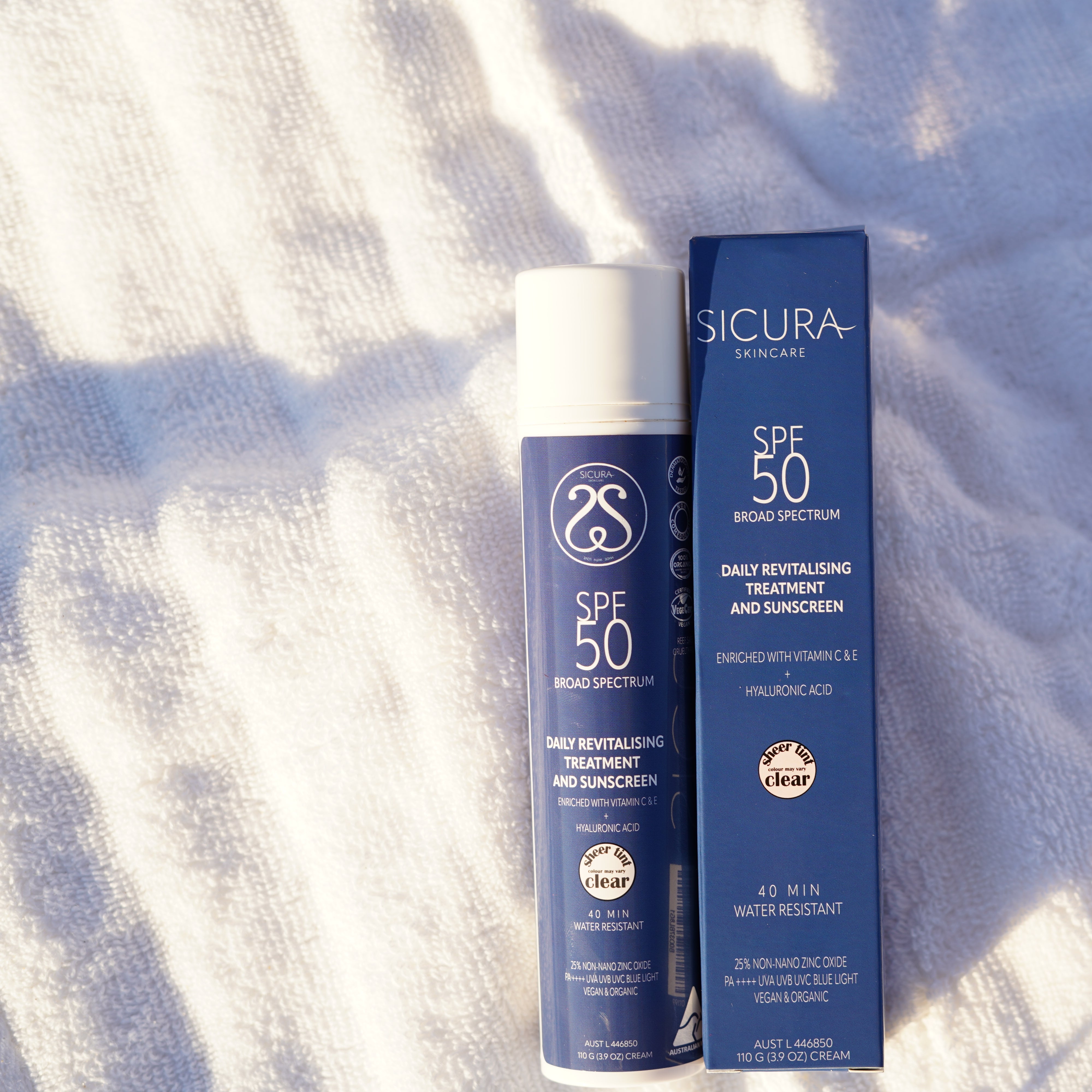 Two sunscreen bottles with SPF 50 on a textured white surface