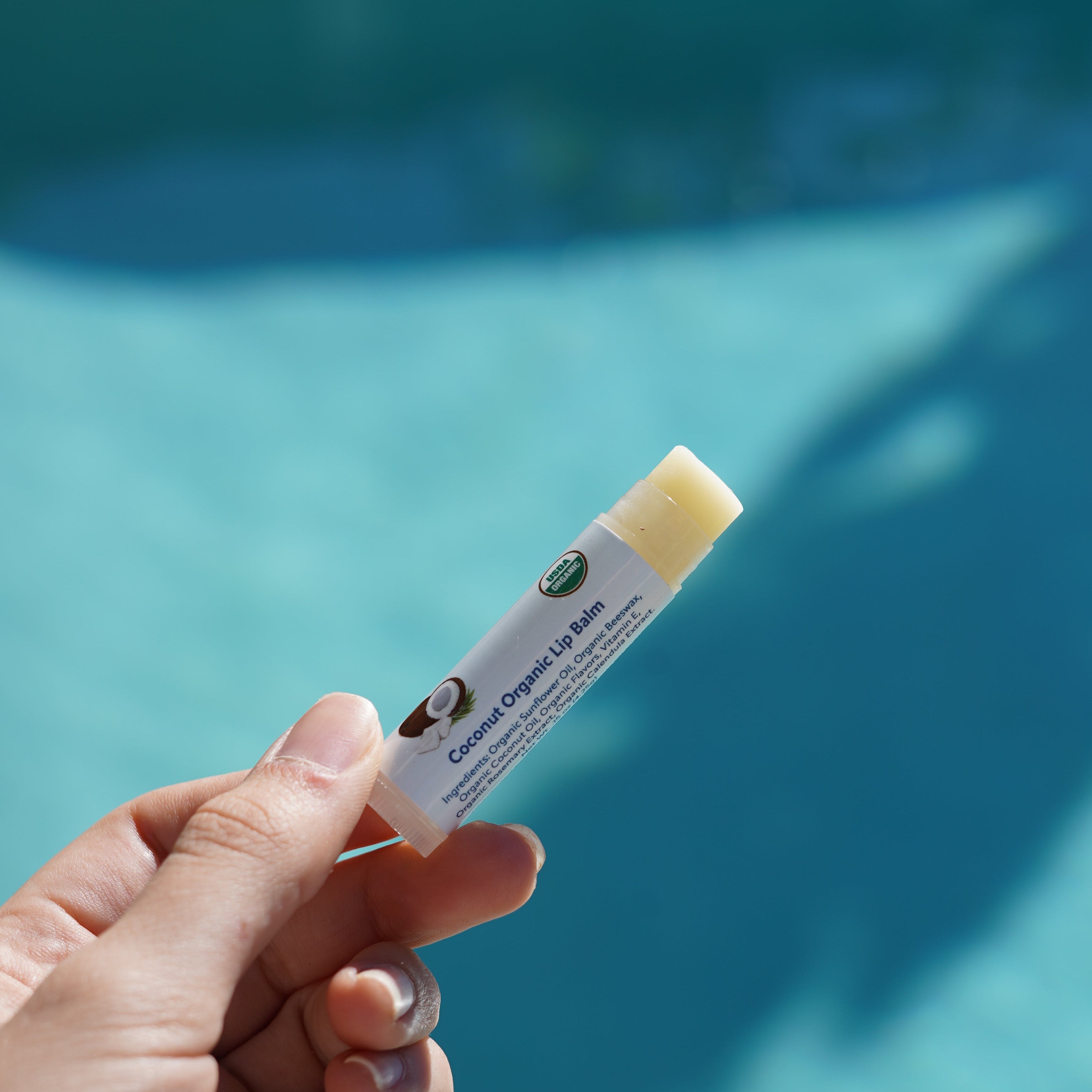 Hand holding a pool test strip with a blurred pool background