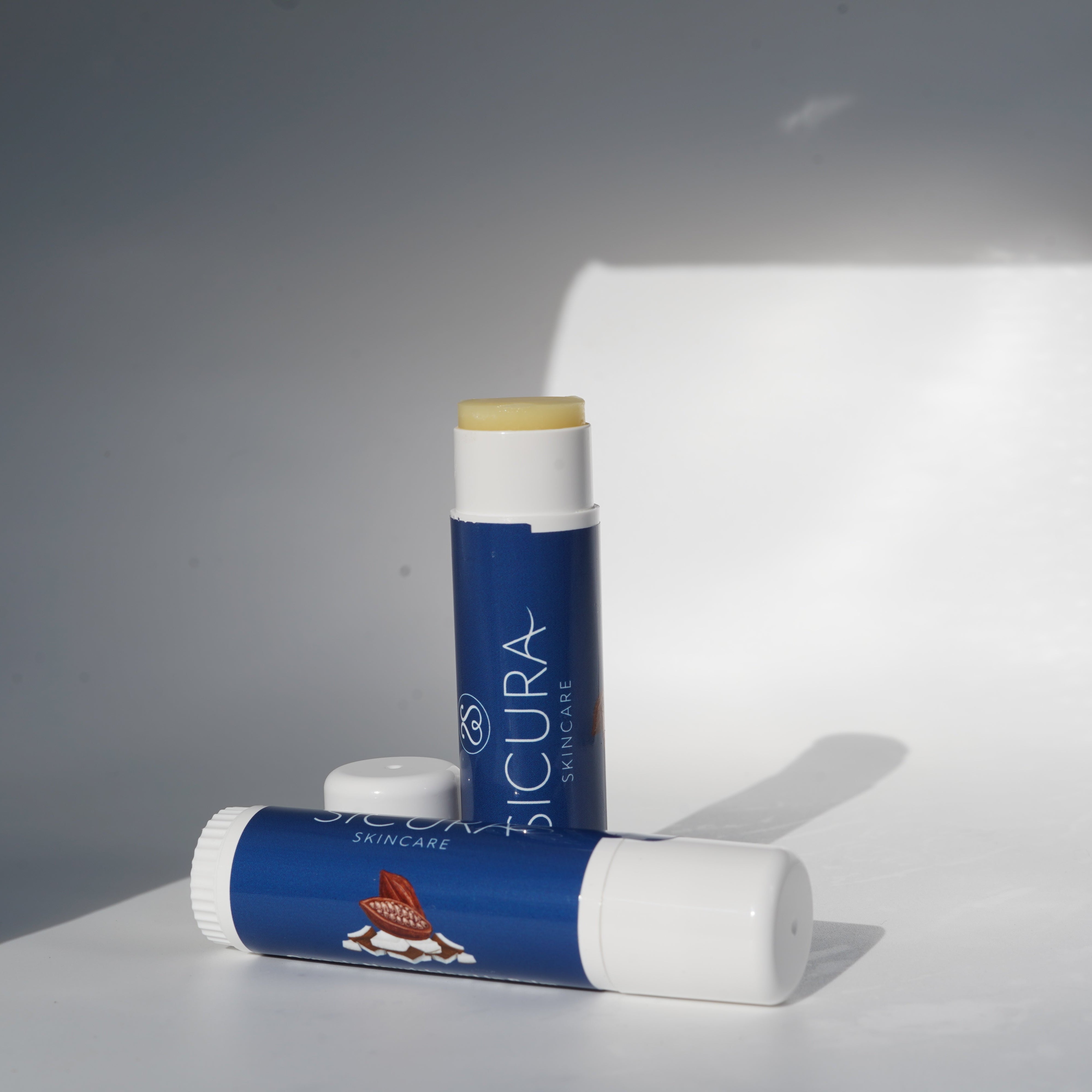 Two Sicura skincare products on a reflective surface with a neutral background