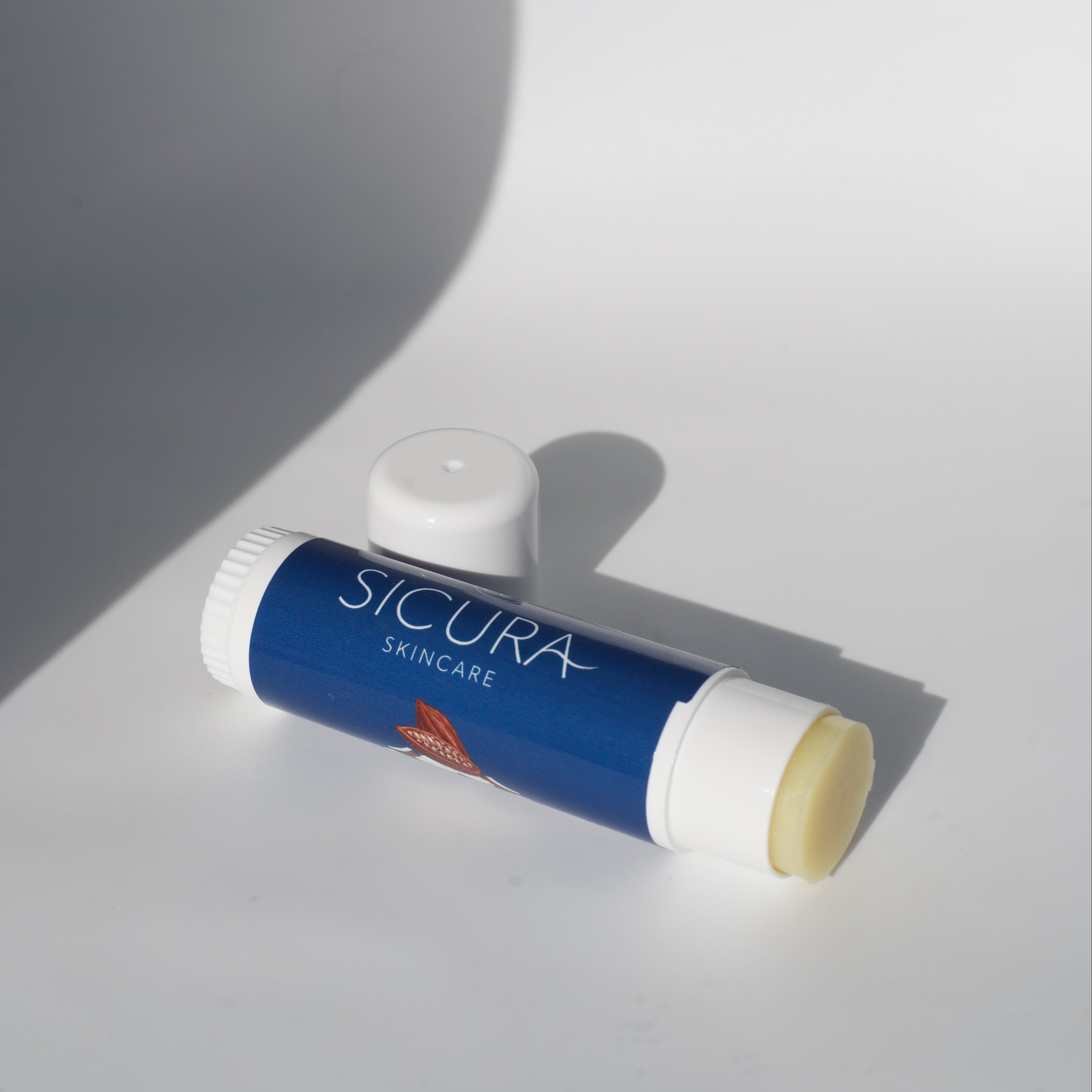Lip balm with 'Sicura Skincare' branding on a white surface