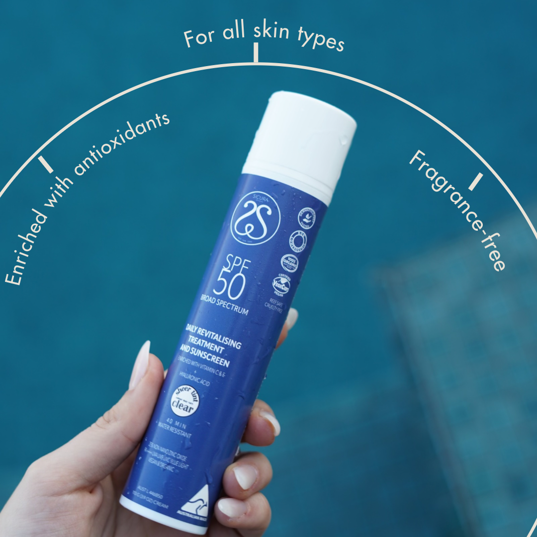 Hand holding a blue sunscreen can with SPF 50 on a blue background