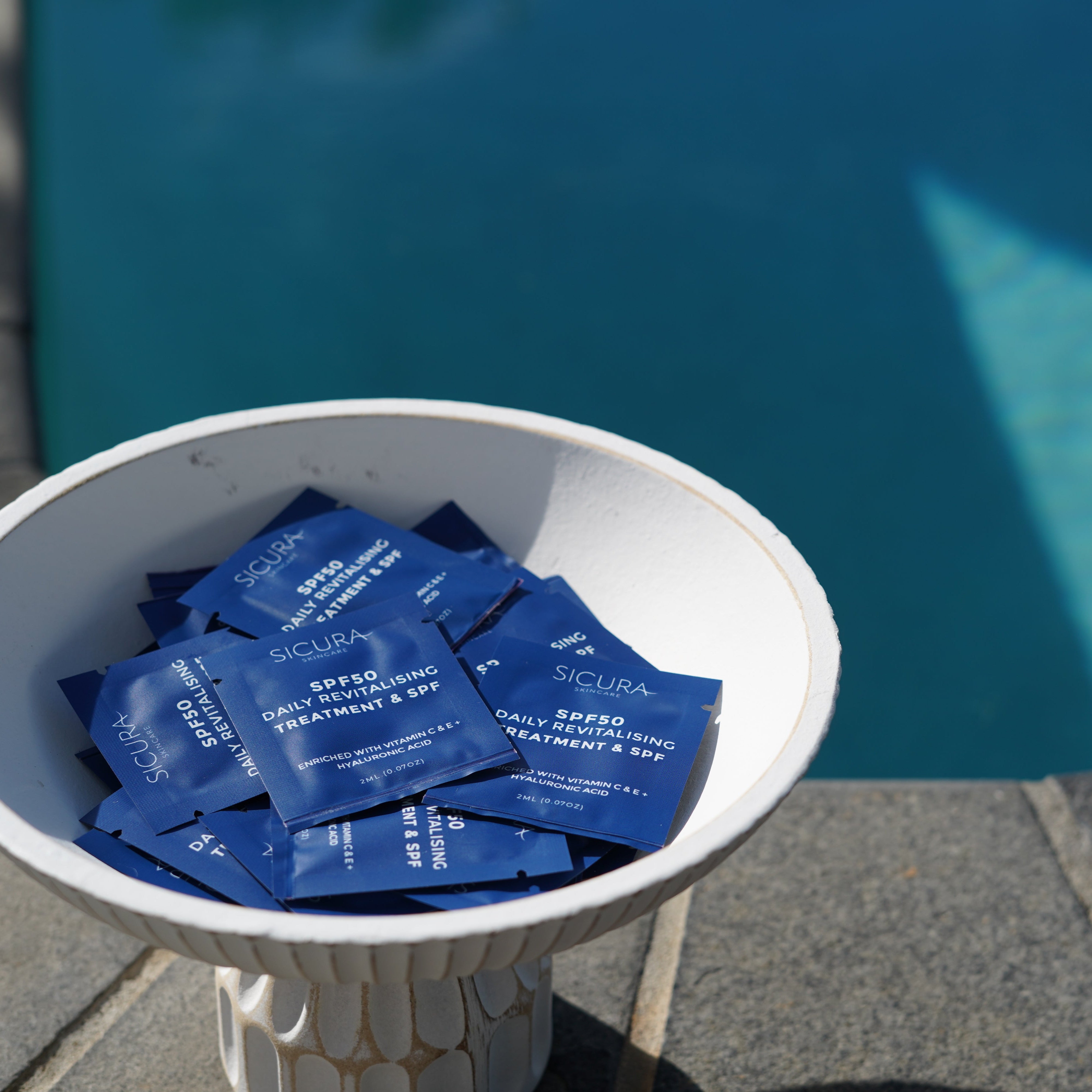White bowl filled with blue packets by a pool