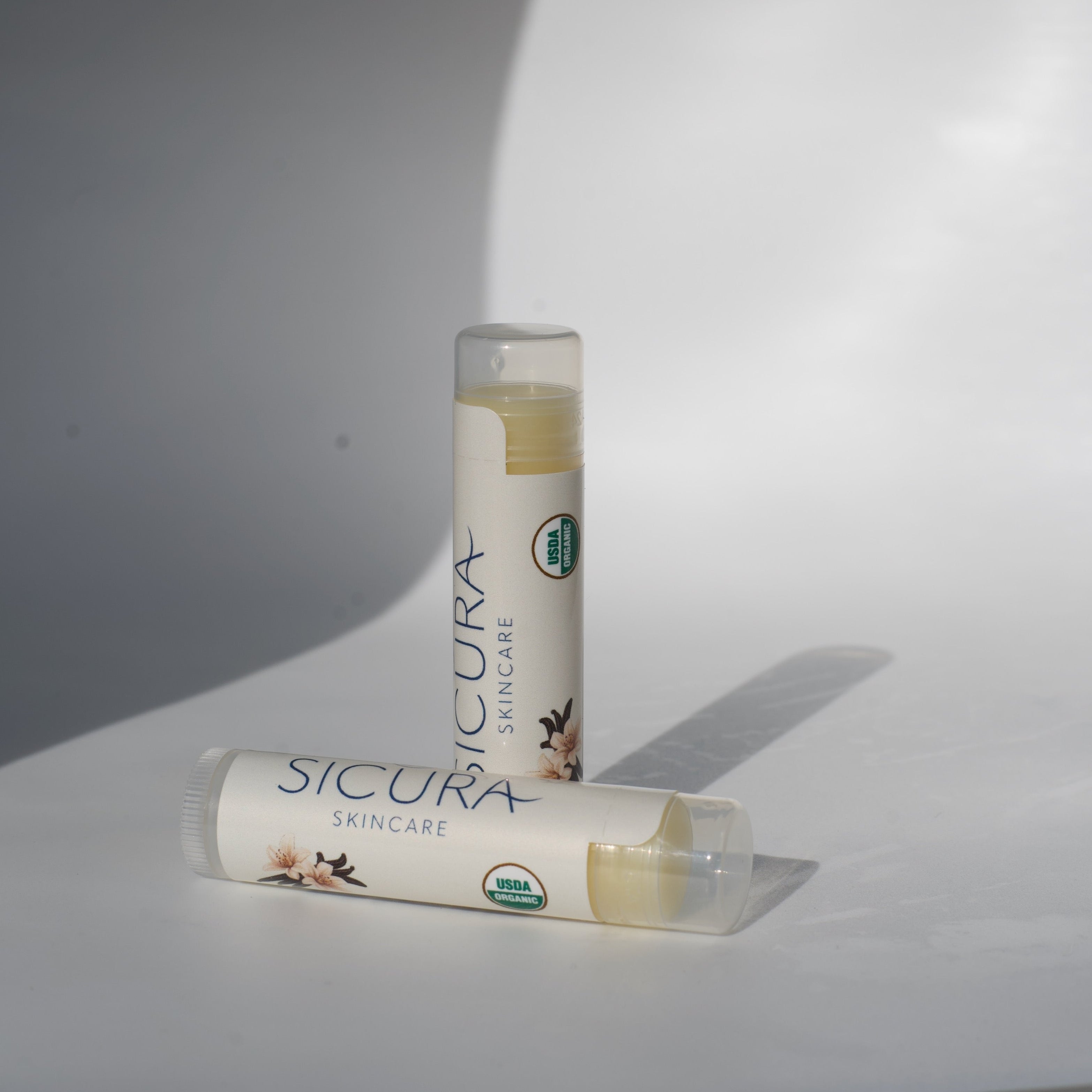 Two Vanilla lip balm tubes labeled 'Sicura' on a white background